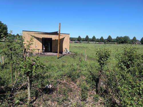 a small wooden building in a field with trees at Natuurhuisje 't Hoogbos - Bosrand in Schijf