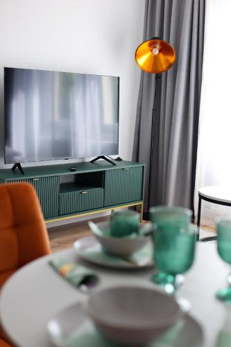 a living room with a tv and a table with dishes at Apartamenty Piast Myślibórz in Myślibórz