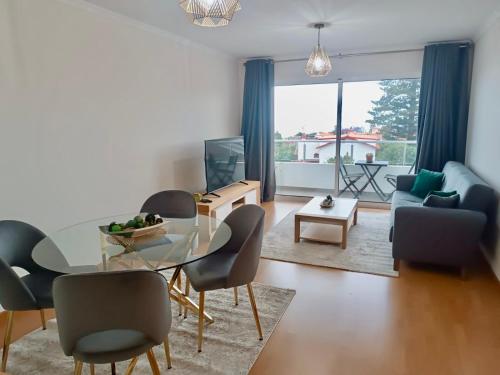 een woonkamer met een glazen tafel en stoelen bij Prestige Solmar - Sea View Apartment - Caniço Center in Caniço