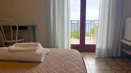 een slaapkamer met een bed en een deur naar een balkon bij Hotel Royal in Villammare