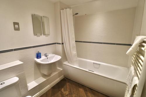 a bathroom with a sink and a tub and a toilet and a sink at Ascot Four Bedroom House With Garden in Ascot