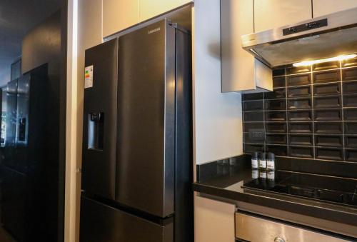 Una cocina con refrigerador y gabinetes de acero inoxidable. en Morada by Wynwood House, en Lima