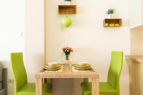 a dining room table with two green chairs at Andy's Home Central Apatment in Budapest