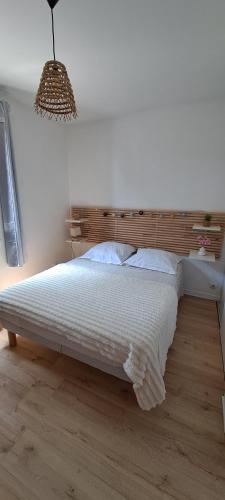 une chambre avec un lit blanc avec une tête de lit en bois dans l'établissement Résidence Le Bali, à La Ciotat
