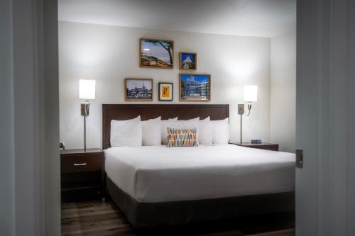 a bedroom with a bed with two lamps and pictures on the wall at Alpine Inn near Convention Center and the Park in Anaheim