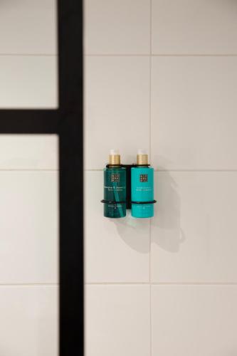 two green bottles sitting on a wall in a bathroom at Hotel Lowietje Lisse - Keukenhof in Lisse