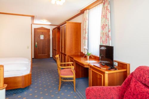 a hotel room with a desk and a bed and a television at Parkhotel an der Therme in Bad Krozingen
