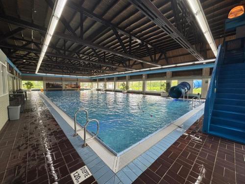 a large swimming pool with blue water in a building at Brand new beachhouse Sand & Meer - Near beach in Bruinisse