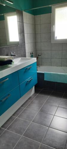 La salle de bains est pourvue d'un lavabo bleu et d'une baignoire. dans l'établissement Jolie maison moderne et sereine à Labenne, à Labenne