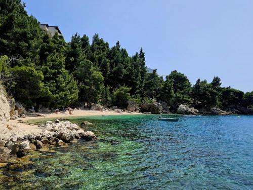 a boat in the water next to a beach at Mala Luka - Omiš, Beach Resort in Stanići