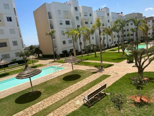 an apartment complex with a swimming pool and palm trees at Brise de Tamaris in Oulad Akkou