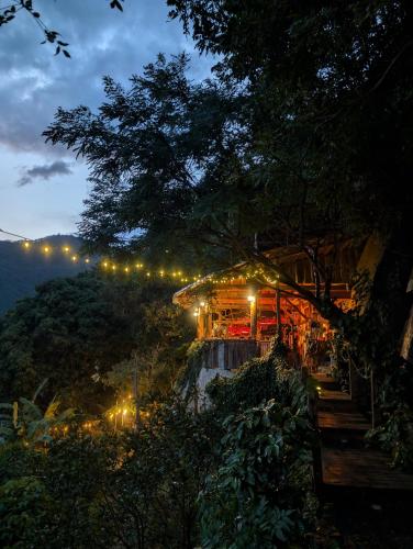 a building with lights on a hill at night at EL PICNIC ATITLÁN in Tzununá