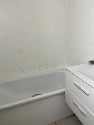 La salle de bains blanche est pourvue d'une baignoire blanche et d'un lavabo. dans l'établissement Appartement T3 pour 4 personnes, à Arles