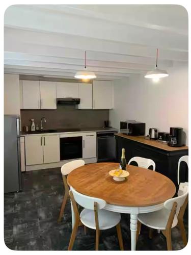 une cuisine avec une table en bois et des armoires blanches dans l'établissement Charmante maison de pêcheur Etretat, à Étretat