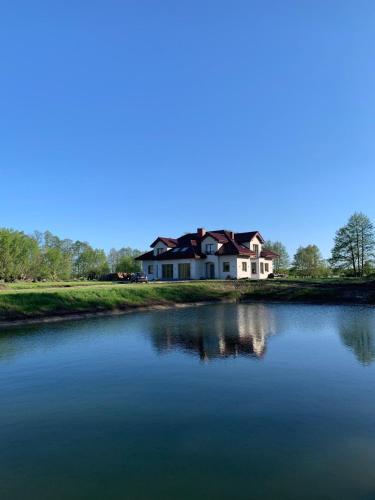 a large house sitting on the side of a lake at Dworek Pod Wierzbami 