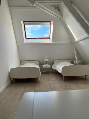 une chambre mansardée avec deux lits et une fenêtre dans l'établissement Villa Relax avec Piscine Privée à 90 min de Paris, à Saint-Hilaire-les-Andrésis