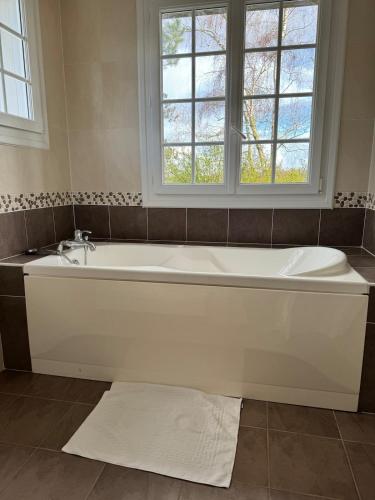 La salle de bains est pourvue d'une baignoire blanche et d'une fenêtre. dans l'établissement Villa Relax avec Piscine Privée à 90 min de Paris, à Saint-Hilaire-les-Andrésis