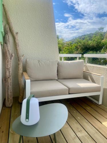 un salon avec un canapé sur un balcon dans l'établissement Mazet vue mer et piscine chauffée, au Lavandou