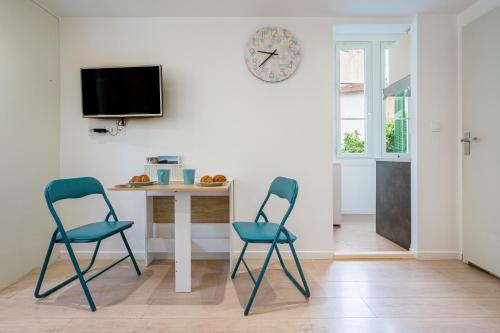 deux chaises dans une pièce avec une table et une horloge dans l'établissement Charmant appartement climatisé à 6min de la mer, à Nice