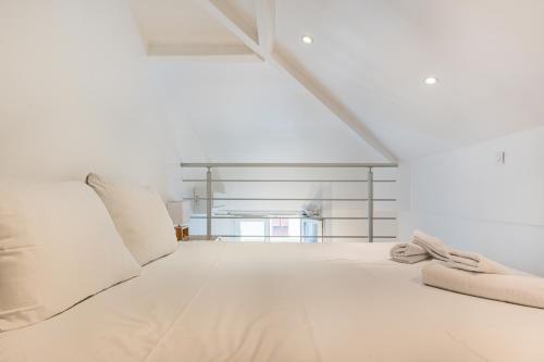 une chambre blanche avec un grand lit avec des oreillers blancs dans l'établissement Charmant appartement climatisé à 6min de la mer, à Nice