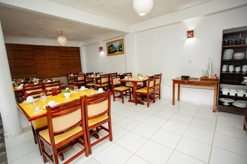 a restaurant with wooden tables and chairs in a room at Pousada dos Girassois Trancoso in Porto Seguro