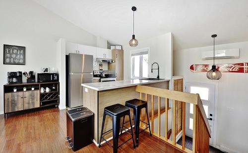 cocina con encimera con nevera y 2 taburetes en 54 chemin de la Perdrix, en Stoneham