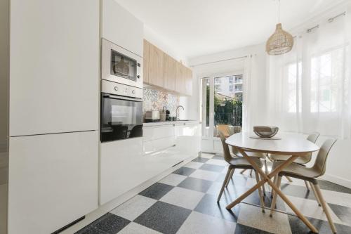 - une cuisine avec des appareils blancs, une table et des chaises dans l'établissement Apartment with garden near the beach, à Antibes