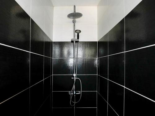 La salle de bains est pourvue d'une douche et de carrelage noir. dans l'établissement La maison du cerf, à Bergues