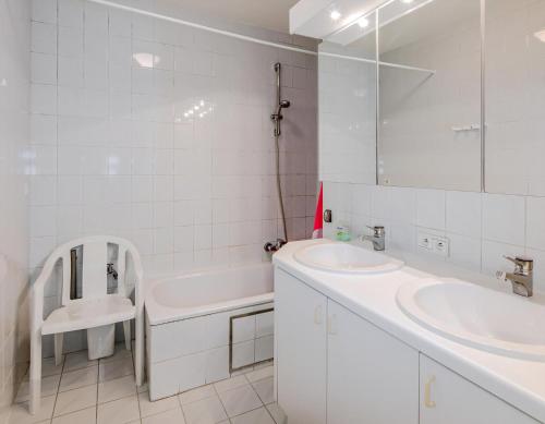 a white bathroom with two sinks and a tub and a mirror at Grand Hotel D3 G in Oostduinkerke