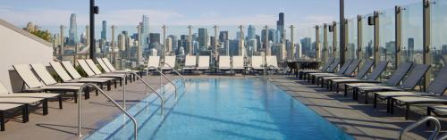 a rooftop pool with chairs and a city skyline at Foundry Unmatched Skyline Views at Lincoln Park in Chicago