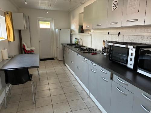 une cuisine avec des armoires blanches et un comptoir noir dans l'établissement Comme à la maison !, à Chavanoz