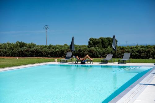 a person sitting in a chair next to a swimming pool at Il Casale nel Parco in Ostuni