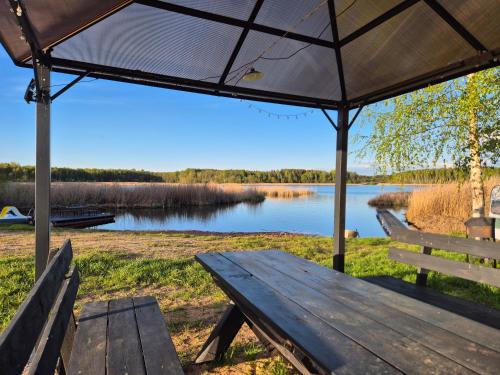 a picnic table with an umbrella in front of a lake at Atpūtas vieta Sīvera Medniekkrasti 