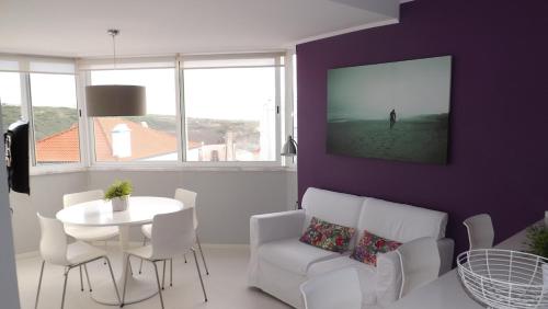 a living room with a white table and a purple wall at Apple Beach Apartment in Colares