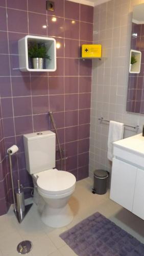 a bathroom with a toilet and a purple tiled wall at Apple Beach Apartment in Colares