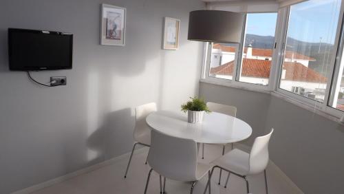 a white dining room with a white table and chairs at Apple Beach Apartment in Colares