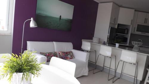 ColaresにあるApple Beach Apartmentの白い椅子と紫色の壁のあるリビングルーム