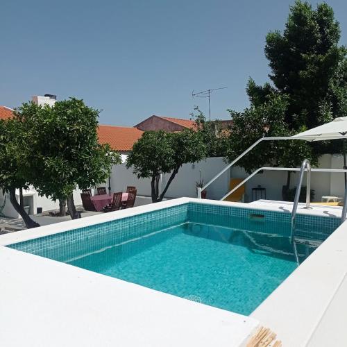 a swimming pool in a yard with an umbrella at Casa da Vila in Mourão