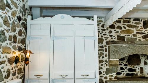 a white cabinet in a room with a stone fireplace at Rodakas Rooms-Ariadni in Kondiás