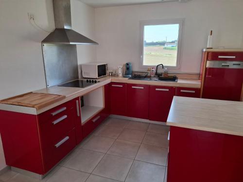 d'une cuisine avec des placards rouges, un évier et une fenêtre. dans l'établissement Maison de vacances avec jardin au Pays-Basque 88 m2, à Guiche