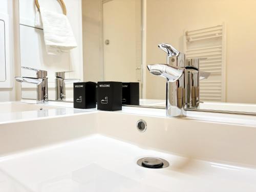 un lavabo de salle de bain avec deux robinets et un miroir dans l'établissement Le Saphir Disney 8mn Gare 7min PARIS Parking x2, à Chessy