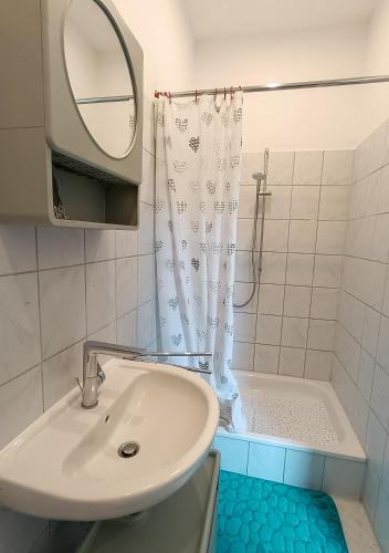a bathroom with a sink and a shower with a mirror at Wohnung am Schlosspark in Bendorf