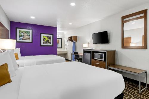 a hotel room with two beds and a tv at Rodeway Inn Carlsbad Caverns Area in Carlsbad