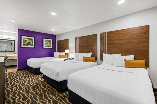 two beds in a hotel room with purple walls at Rodeway Inn Carlsbad Caverns Area in Carlsbad