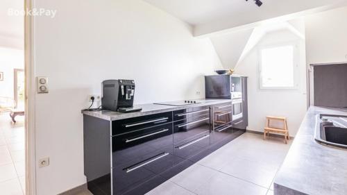 une cuisine avec une cuisine noire et blanche dans l'établissement Échappée Belle, à La Celle-sous-Gouzon