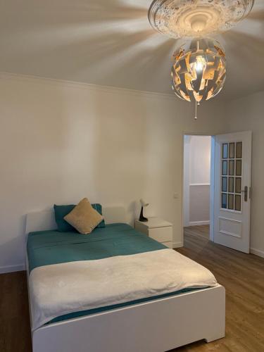 a bedroom with a bed and a chandelier at Casa de Ferias apartamento T3 in Carregado