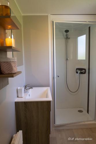 La salle de bains est pourvue d'une douche et d'un lavabo blanc. dans l'établissement Mobil-home convivial avec vue sur mer - Pleubian, à Pleubian