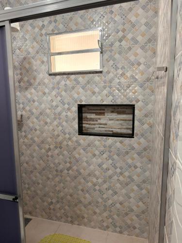 a shower with a glass door and a window at Casa 2min do Centro c Piscina in Bonito