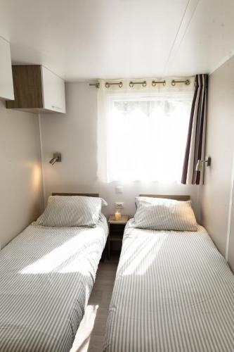 deux lits dans une petite pièce avec une fenêtre dans l'établissement Mobil-home convivial avec vue sur mer - Pleubian, à Pleubian