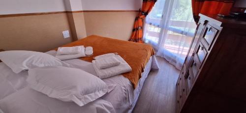 a small bed with white pillows and an orange blanket at El Chozo in La Pinilla